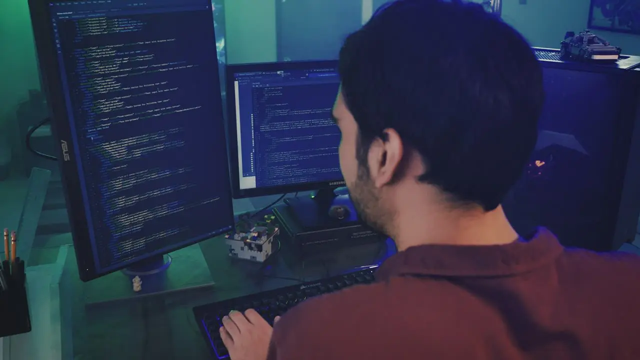 An engineer reviews code across two monitors