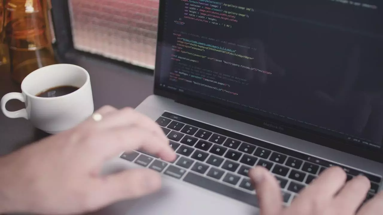 A software developer works with a coffee beside the keyboard